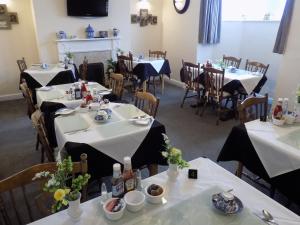 a dining room with tables and chairs with white tablecloths at Belle View in Skegness