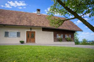 a white house with a brown door and a yard at Winzerhaus am Eichberg in Leutschach +6 photos
