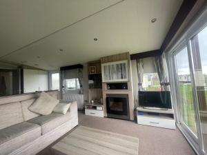 a living room with a couch and a tv at Shells at Sandylands in Stevenston