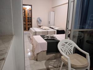 two beds in a room with a chair and a mirror at Hospedagem Porto Barra in Salvador