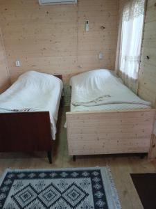a room with two beds and a window and a rug at Riverside Cottage in Martvili
