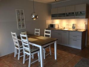 een keuken met een houten tafel en witte stoelen bij Ferienwohnung Möwe in Glowe