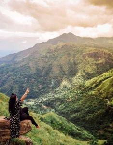 a woman sitting on a rock overlooking a valley at oasis in Ella