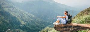 a woman sitting on top of a rock overlooking a valley at oasis in Ella