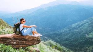 a woman sitting on a rock with a backpack at oasis in Ella