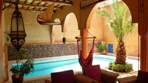 a swimming pool in a house with palm trees at Riad Timadrouine in Tinerhir