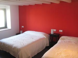 two beds in a room with red walls at Casa Rural El Bornizo con psicina jacuzzi climatizado barbacoa y jardín en Salamanca in Pastores