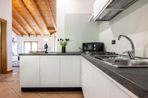 a kitchen with white cabinets and a sink at Appartamento Al Forte e Appartamento Orizzonte59 in Nago-Torbole +42 photos