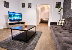 a living room with a couch and a table with a television at Matchday Mile House Walk to Anfield sleeps 8 in Liverpool +53 photos