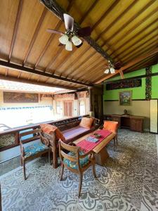 a living room with a table and a ceiling fan at Amelia Villa in Montongbuwoh