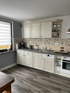 a kitchen with white cabinets and a sink at Mila's Fewo in Stollberg