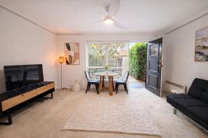 a living room with a table and chairs and a tv at Moonya Courtyard in Carnegie