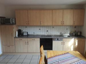 eine Küche mit Holzschränken, Spüle und Tisch in der Unterkunft FeWo Thul in Plein + 8 Fotos