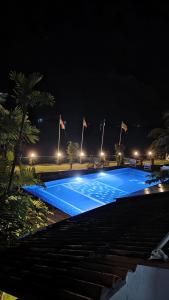a large blue swimming pool at night with flags at Lausanne villa in Dharga Town