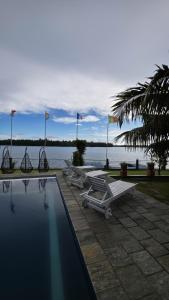 a row of lounge chairs and a pool in front of the water at Lausanne villa in Dharga Town +6 photos