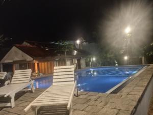 two white chairs sitting next to a swimming pool at night at Lausanne villa in Dharga Town