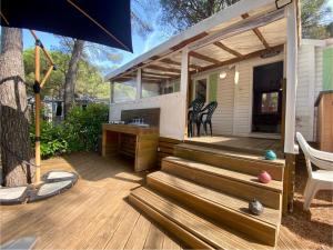 a house with a deck with chairs and an umbrella at Mobil-home Oasis Village Club in Puget-sur-Argens