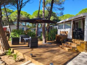 an rv deck with an umbrella and a table and chairs at Mobil-home Oasis Village Club in Puget-sur-Argens