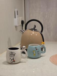 a tea kettle and two cups on a counter at Khobar Luxury Apartments in Al Khobar