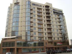 a tall building with cars parked in front of it at Hostel Sofia in Zhytomyr