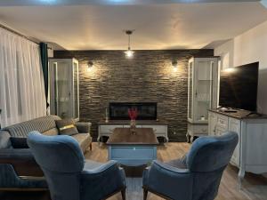 a living room with a couch and chairs and a tv at Boierița Home Stay in Fundu Moldovei