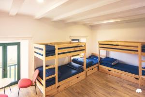 a room with three bunk beds and a table and chairs at Albergue La Incera in San Martín