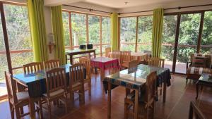 a dining room with tables and chairs and windows at El Encanto Sorata in Sorata