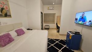 a bedroom with a white bed and a flat screen tv at The Basileia Court in Janman
