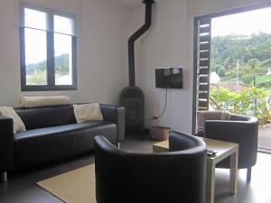 a living room with a couch and chairs and a tv at Casa Das Furnas in Furnas