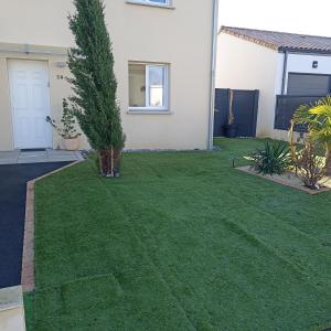 a yard with green grass and a house at Chambre privée in Montaigu-Vendée