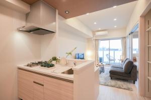a kitchen with a sink and a living room at AYA Residence大阪城公園 Osaka Castle JR Morinomiya 徒歩5min in Osaka
