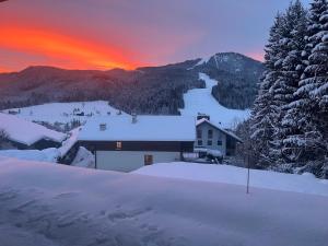 a house in the snow with the sunset in the background at The Mountain Nest in Russbach am Pass Gschütt
