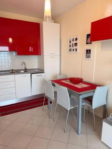 a kitchen with a table and chairs and red cabinets at Torre 13F SeaView Studio in Lignano Sabbiadoro