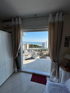 a room with a large window with a view of a city at Torre 13F SeaView Studio in Lignano Sabbiadoro