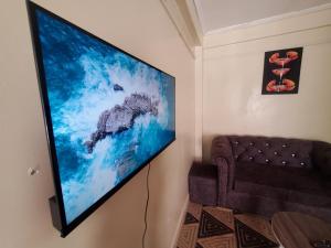 a flat screen tv hanging on a wall next to a couch at Nimmoh home in Rungiri