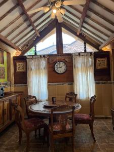 a dining room with a table and a clock on the wall at Amelia Villa in Montongbuwoh +4 photos