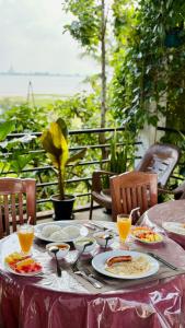 a table with plates of food and glasses of orange juice at Lake Edge Resort in Anuradhapura