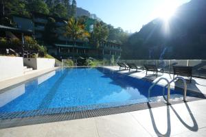 a large swimming pool with two chairs next to a building at Ramboda Falls PLC in Ramboda