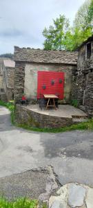 a picnic table in front of a building with a red door at Maison au calme entre Causses and Cévennes in Barre-des-Cévennes