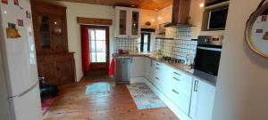 a kitchen with white cabinets and a wooden floor at Maison au calme entre Causses and Cévennes in Barre-des-Cévennes
