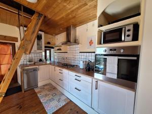 a kitchen with white cabinets and stainless steel appliances at Maison au calme entre Causses and Cévennes in Barre-des-Cévennes +26 photos