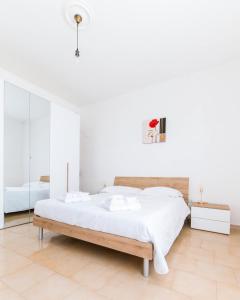 a white bedroom with a bed and a mirror at Losa Rooms in Abbasanta