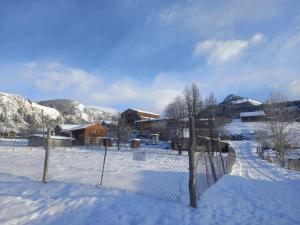 a fence covered in snow next to a river at Tusheti Winter Home in Omalo