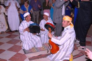 Un groupe d'hommes dans des turbans assis sur le sol dans l'établissement Ksar Timnay Hotel, à Aguelmous