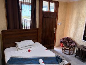 a bedroom with two beds and a door and a chair at Karafuu Nyama Choma Lodge in Bwejuu