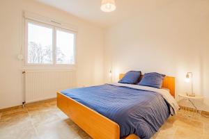 a bedroom with a bed with blue sheets and a window at La Maison du Lac in Montceau-les-Mines