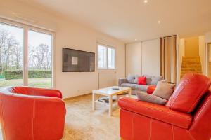 a living room with two red chairs and a couch at La Maison du Lac in Montceau-les-Mines