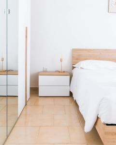 a bedroom with a white bed and a wooden floor at Losa Rooms in Abbasanta