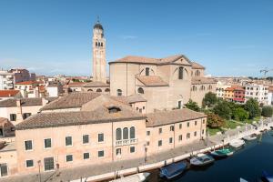 a city with a clock tower and a river with boats at Alloggi Venca' in Chioggia