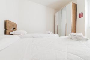 two beds in a white room with white sheets at Losa Rooms in Abbasanta